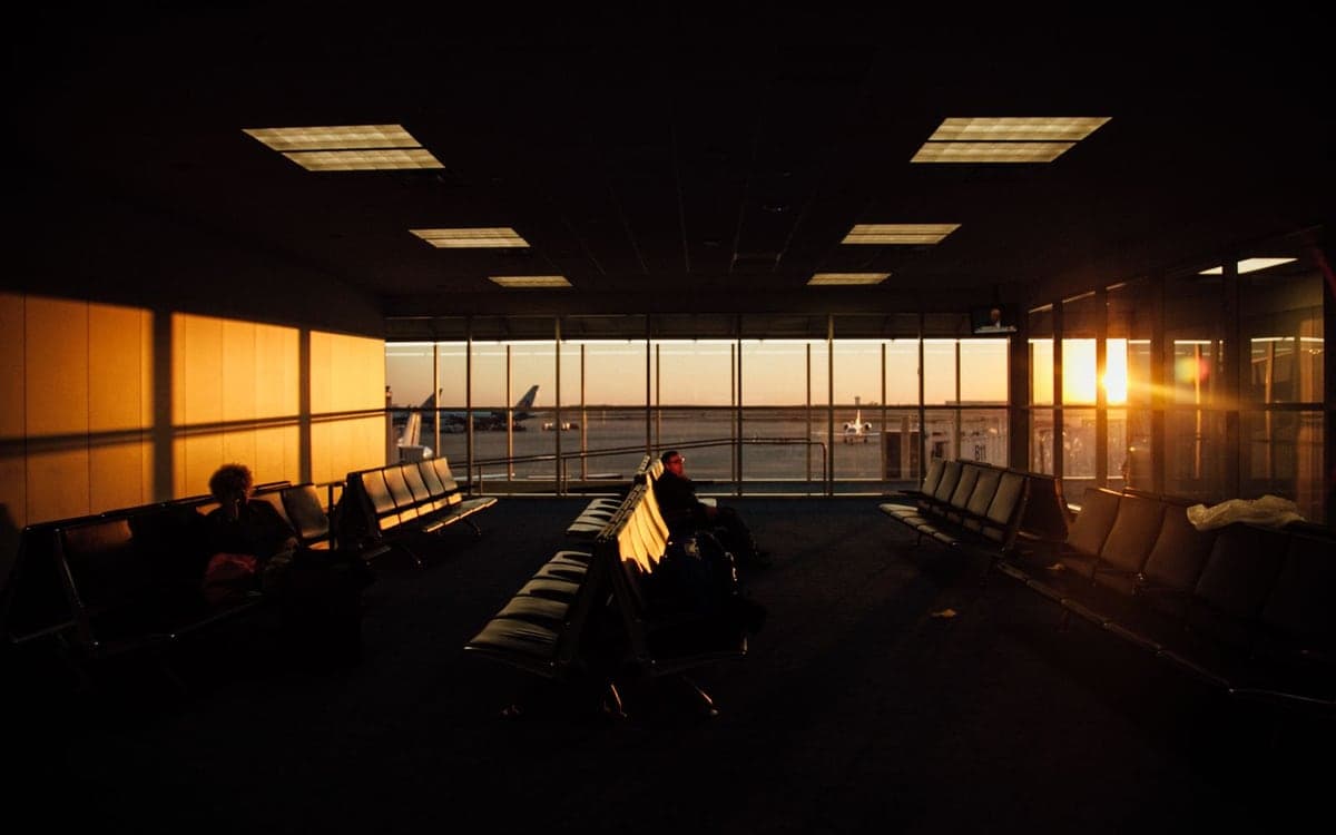 An airport departure lounge at golden hour, planes on the apron beyond